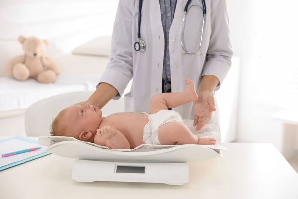 Doctor weighting cute baby in clinic, closeup. Health care - Foto, imagen