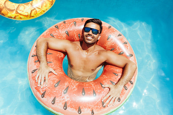 Handsome man relaxing alone on a float in the pool on a hot summer day - Foto, Bild
