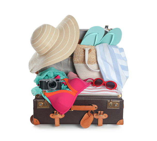 Open vintage suitcase with different beach objects packed for summer vacation isolated on white - Фото, зображення