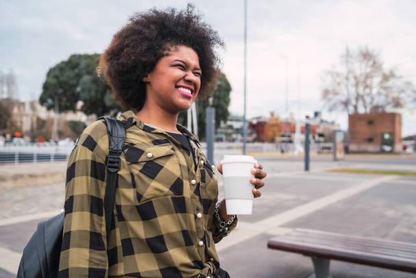 Portrait of beautiful afro american latin woman holding a cup of coffee outdoors in the street. Urban concept. - Fotoğraf, Görsel