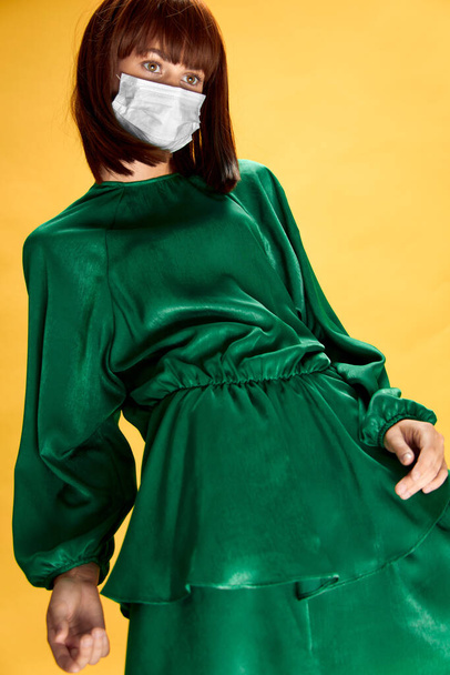 Frau im Modekleid posiert mit medizinischer Maske Virus covid-19 - Foto, Bild