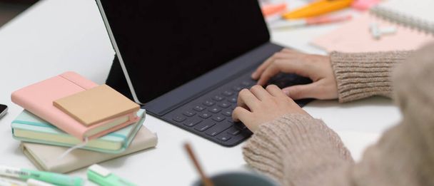 Vista da vicino della studentessa che fa assegnamento con tablet digitale e cancelleria sul tavolo di studio - Foto, immagini