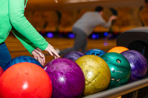 Les mains de l'enfant atteignent pour ramasser la boule de bowling à Bowling ruelle - Photo, image