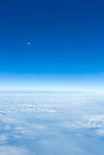 wolk en lucht met maan gezien door het raam van het vliegtuig - Foto, afbeelding