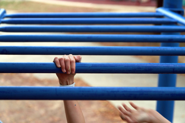 Mãos de crianças em movimento em bares de macacos enquanto brincam no parque infantil
 - Foto, Imagem