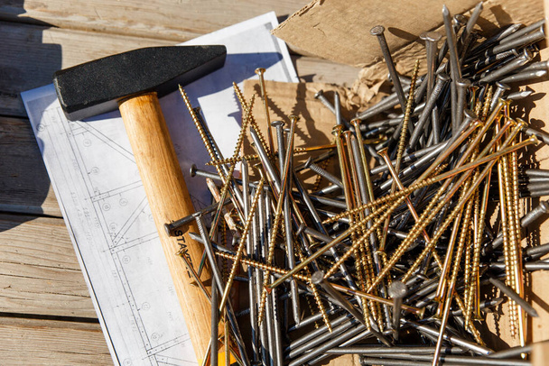 A hammer and Long nails with self-tapping screws lie on the drawing of the house construction plan. Preparation for construction. Abakan, Russia-April 6, 2020. - Valokuva, kuva