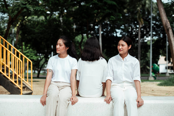 Triple hermana gemela sentada en el banco de mármol en el patio del parque
. - Foto, Imagen
