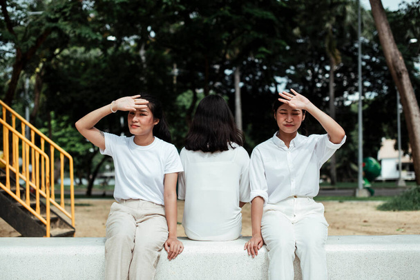 Triple hermana gemela sentada en el banco de mármol en el patio del parque
. - Foto, Imagen