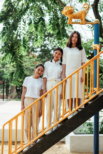 Triple δίδυμη αδελφή στέκεται στη σκάλα του παιχνιδιού στην παιδική χαρά. - Φωτογραφία, εικόνα