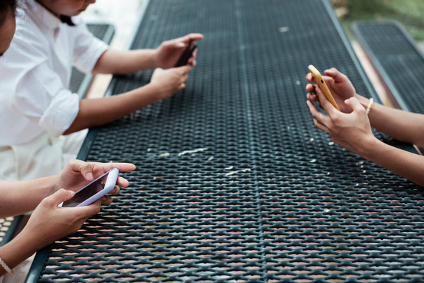 Image recadrée de trois smartphones dans les mains de ttriple twin sur la table en métal. - Photo, image