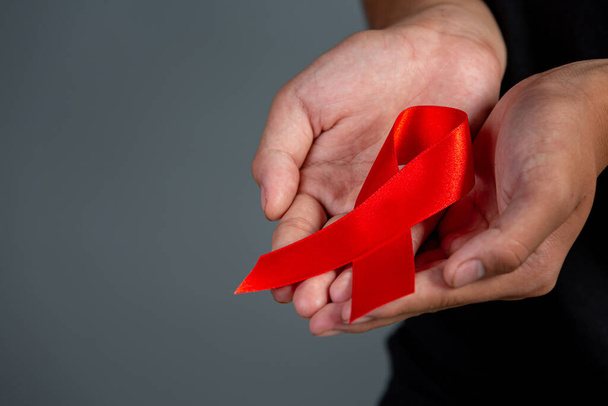 Woman hand holding red ribbon HIV awareness concept World AIDS Day and World Sexual Health Day. - 写真・画像