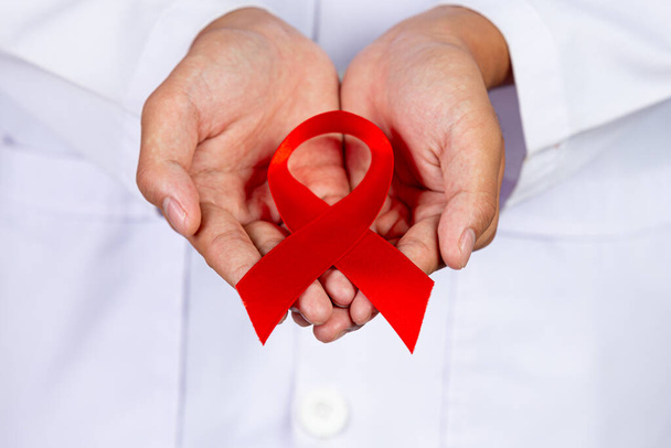 Le médecin tient un ruban rouge, la sensibilisation au VIH, la Journée mondiale du sida et la Journée mondiale de la santé sexuelle. - Photo, image