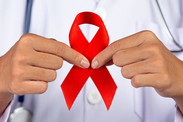 Lekarz ma czerwoną wstążkę, świadomość HIV, Światowy Dzień AIDS i Światowy Dzień Zdrowia Seksualnego. - Zdjęcie, obraz