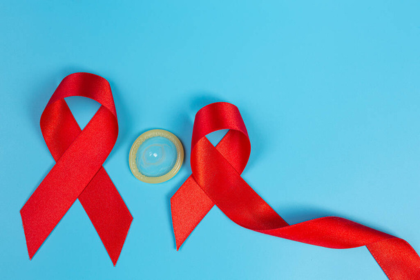Κόκκινη κορδέλα γνώσης και προφυλακτικά Ενημέρωση για τον HIV, Παγκόσμια Ημέρα κατά του AIDS και Παγκόσμια Ημέρα Σεξουαλικής Υγείας. - Φωτογραφία, εικόνα