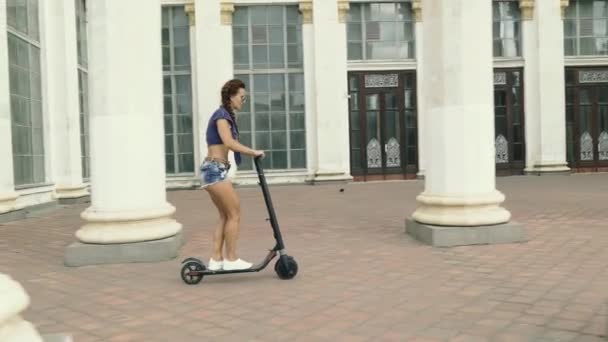 Electric scooter. A young woman is riding an electric scooter. - Materiaali, video