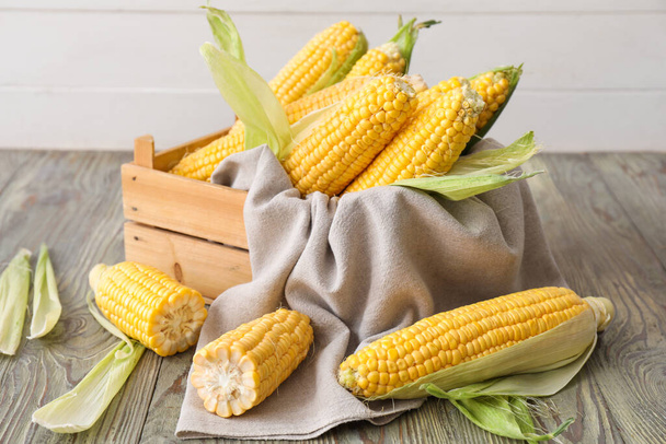 Caja con mazorcas de maíz fresco en la mesa
 - Foto, imagen