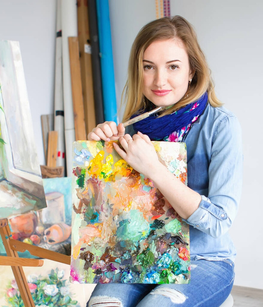 girl artist with a palette of paints in hands. looks directly into the camera. Art studio - Photo, Image