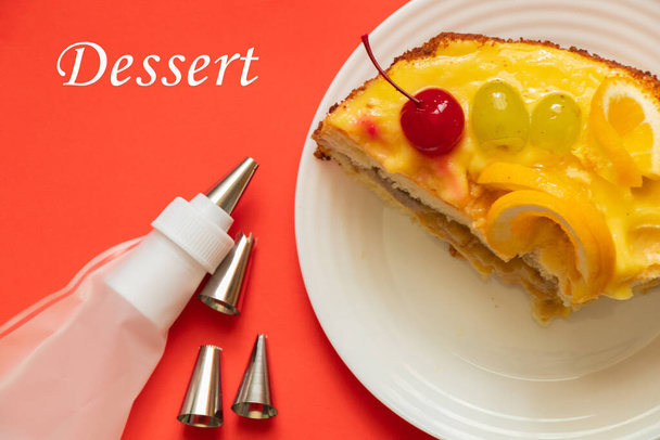 кусок фруктового торта и кондитерская сумка на цветном фоне на день рождения и слово в английском десерте - Фото, изображение