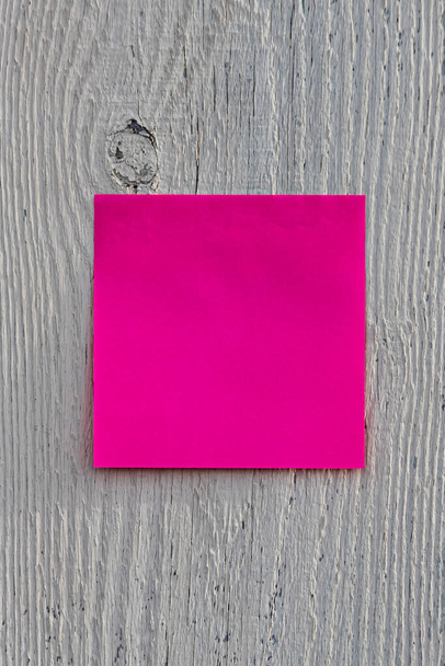 На сером деревянном заборе висит квадратная розовая или красная бумага с копировальным местом. Горизонтальная вертикаль  - Фото, изображение