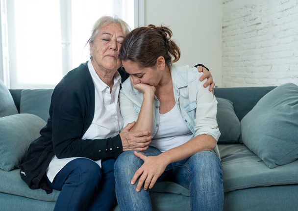 Senior mother comforting adult daughter grieving loss of loved one fighting the Coronavirus. Elderly mother embracing adult daughter suffering from depression. People affected by COVID-19 outbreak. - Foto, imagen