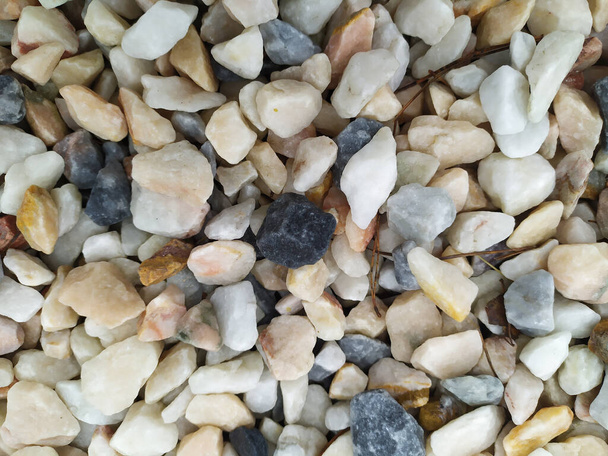 Ακατέργαστα πετρώματα και ορυκτά ως φυσικό πέτρωμα με θρυμματισμένο και ακατέργαστο υλικό σε τραχιά ακτή ή βραχώδη παραλία παρουσιάζουν ψήγματα και ψαμμίτες σε αρμονικά παστέλ χρώματα - Φωτογραφία, εικόνα