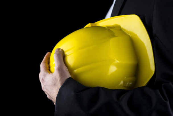 Man in a suit holding a yellow hardhat - Photo, Image