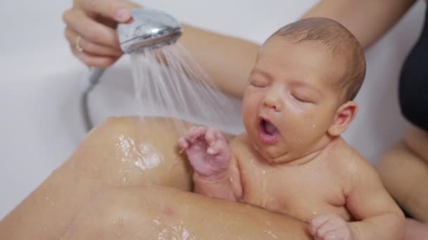 Newborn baby girl is taking bath in bathroom at home. Hygiene and health care for newborn baby. - Πλάνα, βίντεο