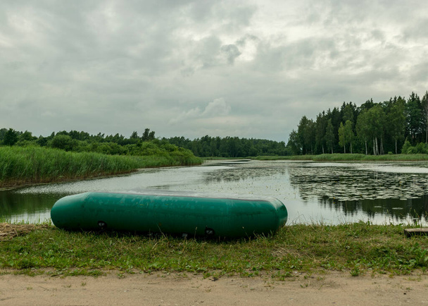 paisagem com barco de borracha verde na costa do lago, conceito de pesca, tempo de lazer na natureza, tempo de verão
 - Foto, Imagem