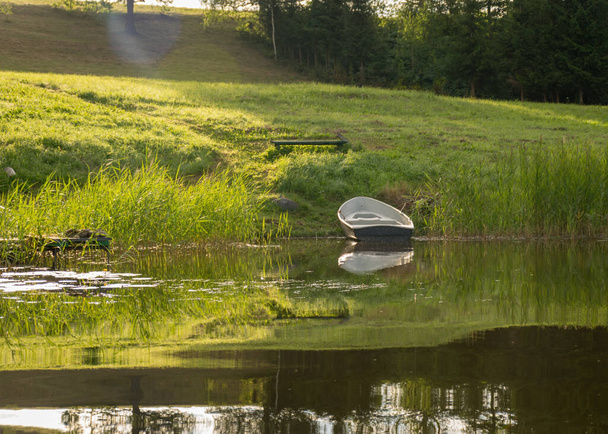 湖の岸のボートの眺め湖の穏やかな水の中の反射夏の朝 - 写真・画像