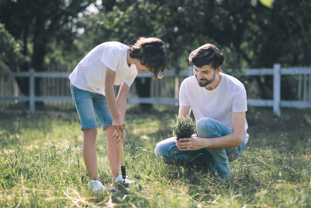 Dark-haired man holding the plant and talking, his son listening to him - Foto, immagini