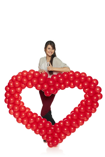 Smiling woman holding red balloon heart - Φωτογραφία, εικόνα