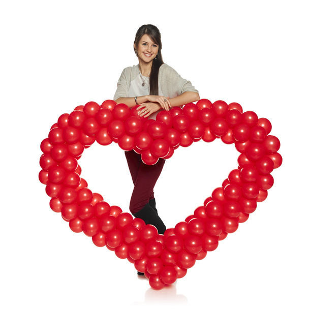 Smiling woman holding red balloon heart - Valokuva, kuva