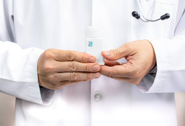 A male doctor holding a white medicine bottle. - Photo, image
