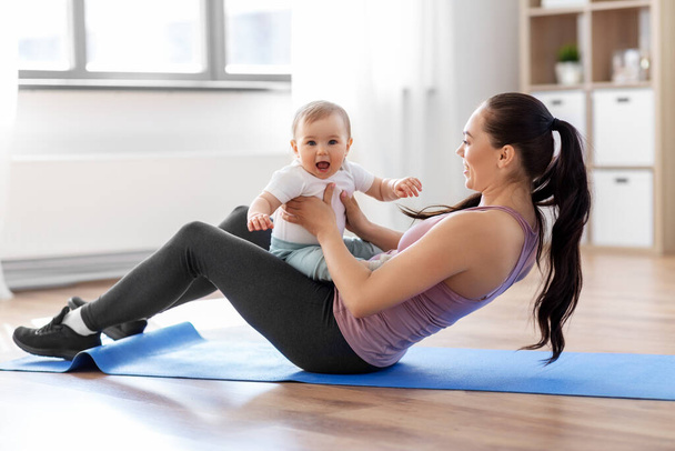 happy mother with little baby exercising at home - Foto, Imagen