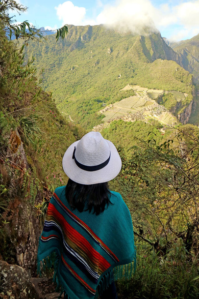 Female traveler impressed by the amazing aerial view of the Inca citadel ruins of Machu Picchu view from Huayna Picchu mountain, Cuzco, Peru - Photo, Image