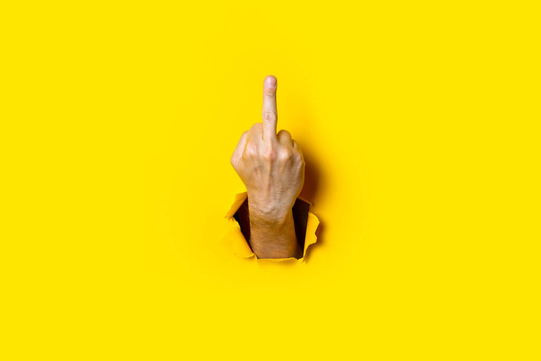 Man's hand showing middle finger, fuck on a yellow background. Hand gestures. - Zdjęcie, obraz