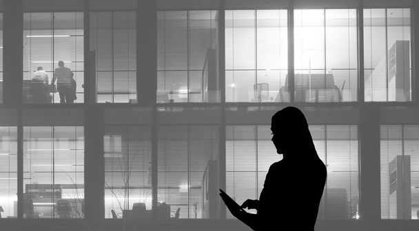 Silhouette of  business woman using tablet on office building background - Foto, Bild