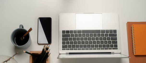 Vista superior da mesa de escritório com laptop, lápis, livros de agenda, smartphone e caneca de café
  - Foto, Imagem