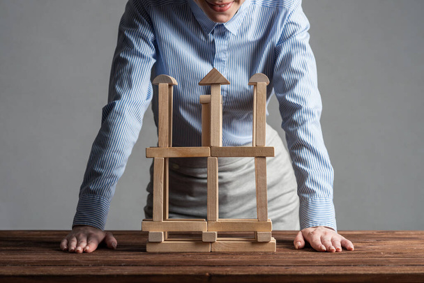 Business woman building construction on table from wooden blocks. Architecture engineering and construction. Company strategy planning, organization and development. Business motivation concept - Foto, immagini
