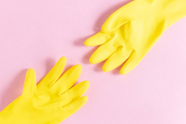A closeup shot of yellow plastic gloves on a pink background - Foto, Imagem