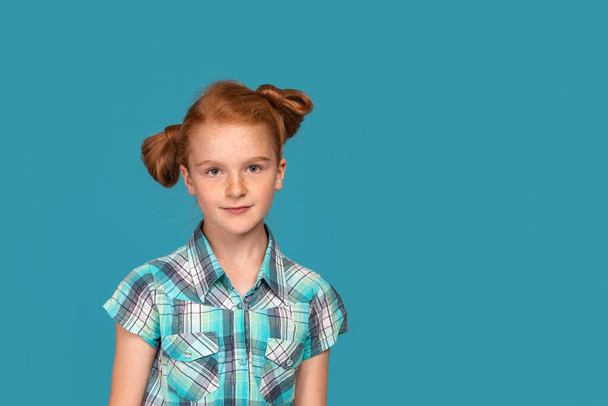 Kırmızı saçlı, mavi gömlekli genç bir kızın duygusal portresi. Stüdyoda mavi arka planda fotokopi alanı olan. - Fotoğraf, Görsel