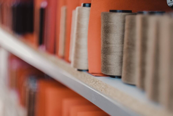 A selective focus shot of sewing thread on the shelves in an atelier - Фото, зображення