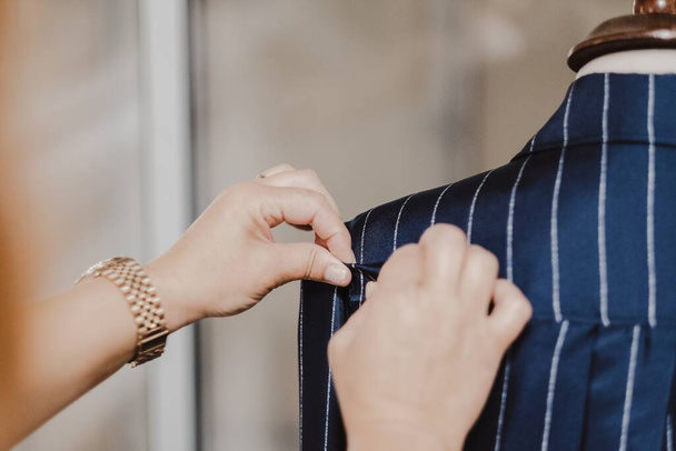 A selective focus shot of a tailor sewing a blue striped shirt on mannequin - Photo, Image