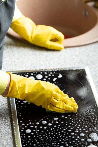 Une personne essuie le plan de travail de la cuisine à l'aide de dégraissant spray détergent nettoyant pour cuisinière - Photo, image