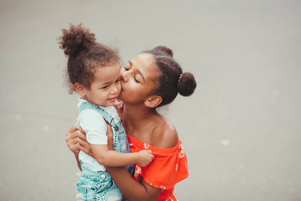 Outdoor picture of senior sister giving a kiss to her baby sister  - Fotó, kép