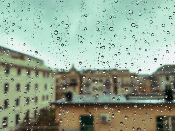 Beautiful photography of the waterdrop over the window. Indoor panoramic view to the city after rain. - Foto, Imagem