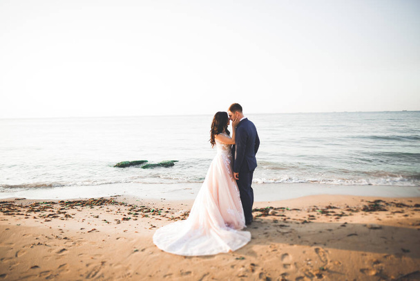 Весільна пара, наречений, наречена з букетом позує біля моря і блакитного неба
 - Фото, зображення