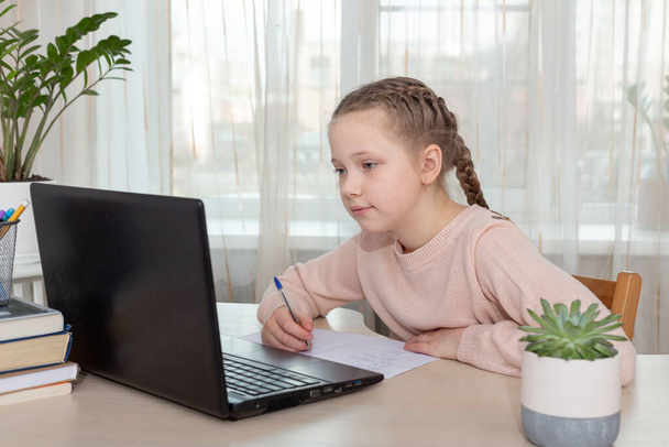 Chica de la escuela sentada en el escritorio y el uso de ordenador portátil en casa. Educación Volver a la escuela - Imagen
 - Foto, imagen