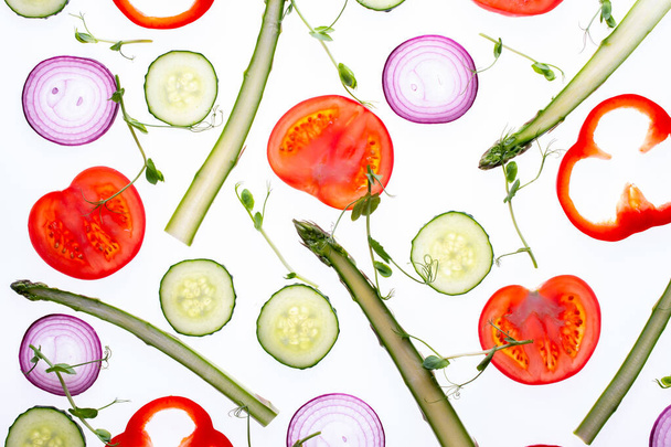 トマトスライス玉ねぎキュウリアスパラマイクログリーンペッパーフラットレイで作られた創造的なレイアウトパターン。食べ物の概念。白地に隔離された野菜. - 写真・画像