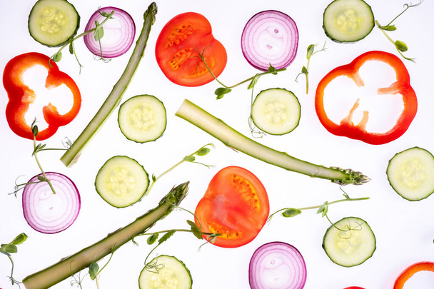 Creative layout pattern made of tomato slice onion cucumber sparagus microgreen pepper Flat lay. Концепция питания. Овощи изолированы на белом фоне. - Фото, изображение